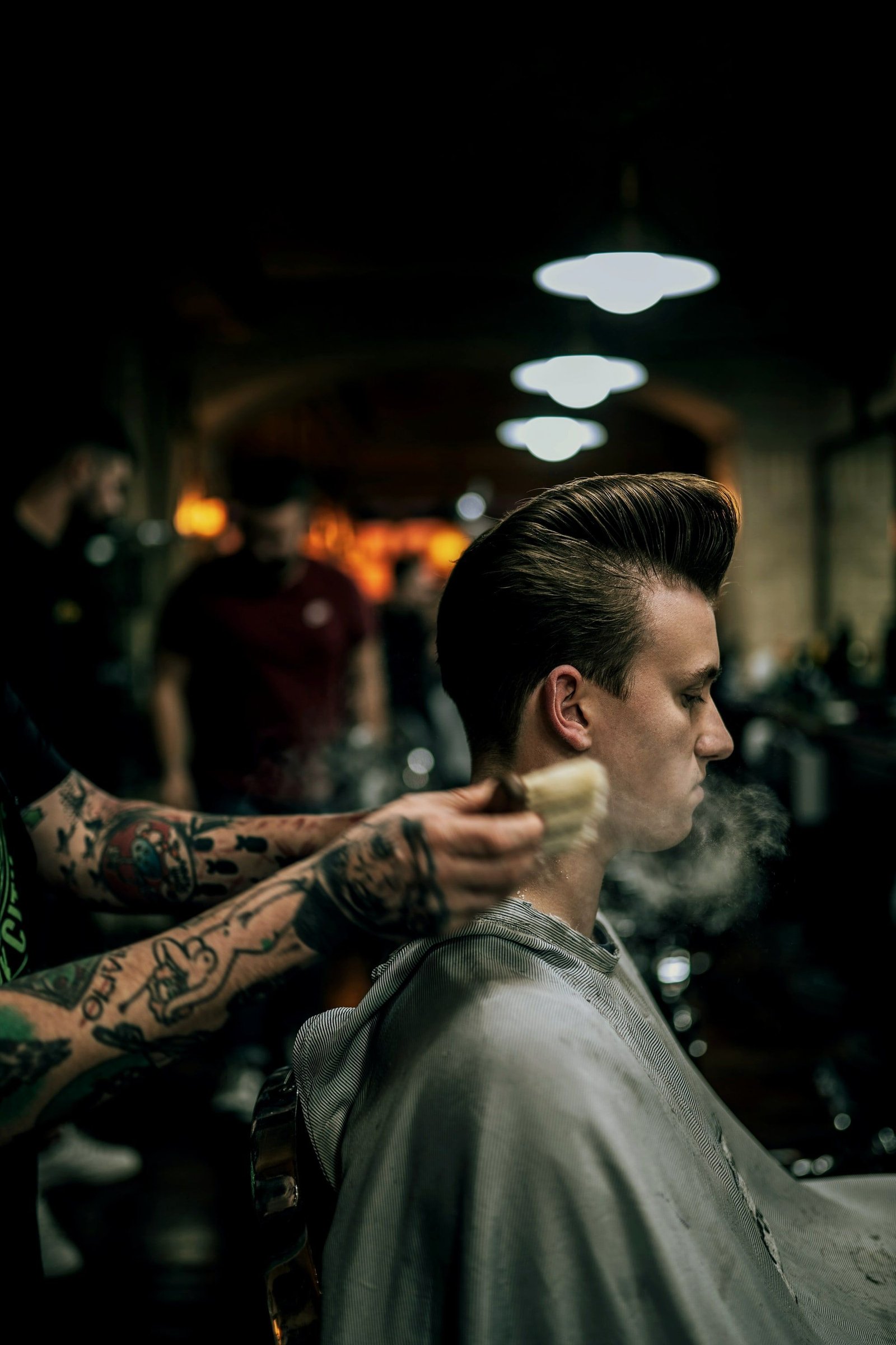 Cliente con pompadour recién peinado mientras el barbero retira el talco
